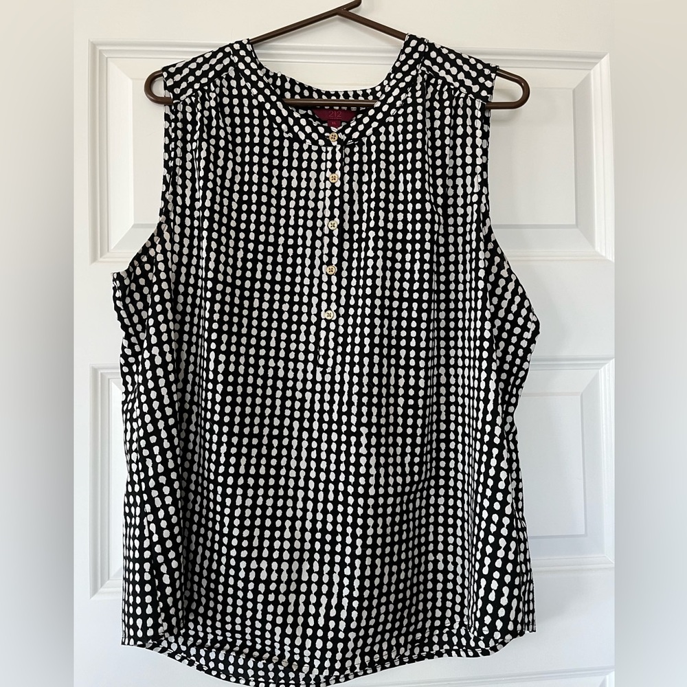 Women’s sleeveless blouse. Black and white with small gold buttons in front.